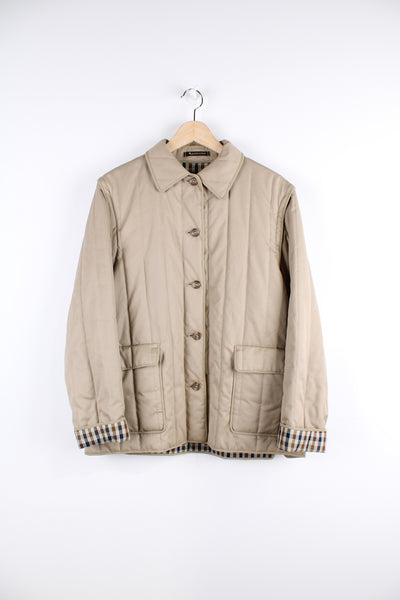 Vintage Aquascutum quilted jacket in a tan colour, button up, has detachable sleeves, two pockets and Aquascutum print lining. 