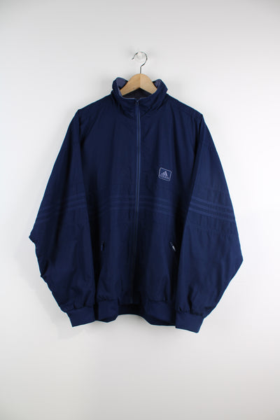 Vintage Adidas navy blue zip through tracksuit top, features embroidered logo on the chest and three stripe details along the chest and sleeves