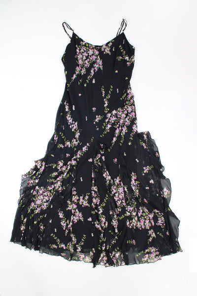 Y2K maxi dress features waterfall ruffled hem, made from a black floral outer layer with black layer underneath. 