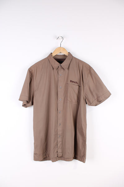 Y2K Bench brown short sleeved, cotton shirt. Features embroidered spell-out logo on the chest and across the back of the shoulders 