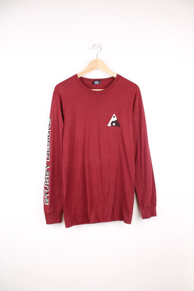 Maroon red Stussy long sleeved t-shirt with yin yang graphic on the front and spell-out graphic down the sleeve 