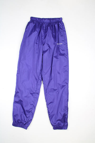 Vintage Reebok tracksuit bottoms in a purple colourway, elasticated waist, cuffed at the bottom and has logo embroidered on the front.