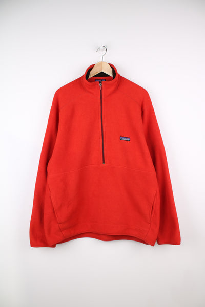 Patagonia Synchilla Fleece in a orange colourway, half zip up, big pouch pocket, and has logo embroidered on the front.
