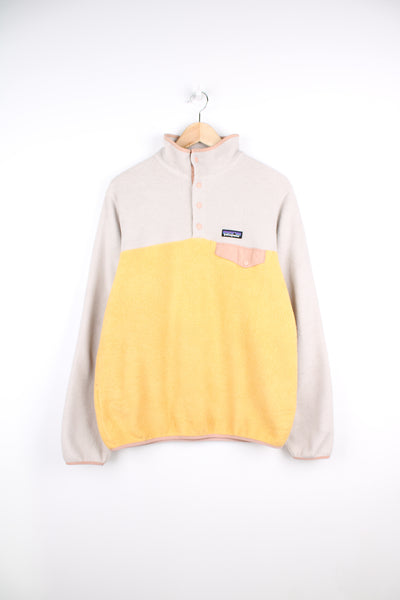 Patagonia Synchilla Fleece in a white and yellow colourway, quarter button up, chest pocket, and has logo embroidered on the front.