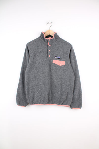Patagonia Synchilla Fleece in a grey and pink colourway, quarter button up, chest pocket and has the logo embroidered on the front.