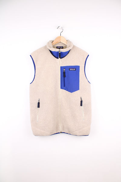 Patagonia Fleece Vest in a tan and blue colourway, zip up, multiple pockets and has the logo embroidered on the chest.