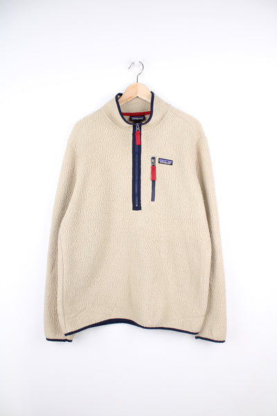 Patagonia Fleece in a tan and blue colourway, half zip up, chest pocket and has the logo embroidered on the chest.