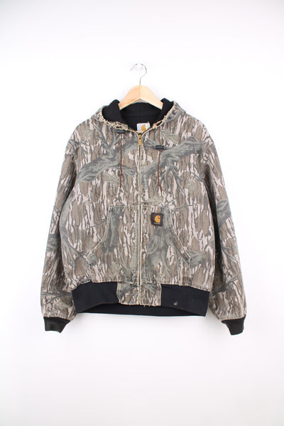 Carhartt Camo Active Jacket in a green and brown real tree camo colourway, heavy cotton lining, zip up, hooded and has the logo embroidered on the pocket.