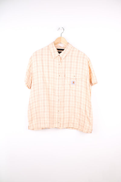 Carhartt Plaid Short Sleeve Shirt in a tan and red colourway, button up, cropped fit, has hidden side pockets, and also has the logo embroidered on the chest pocket.
