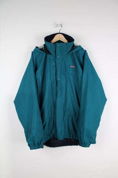 Patagonia outdoor jacket in blue, zip up, side pockets, hooded and has embroidered logo on the front.