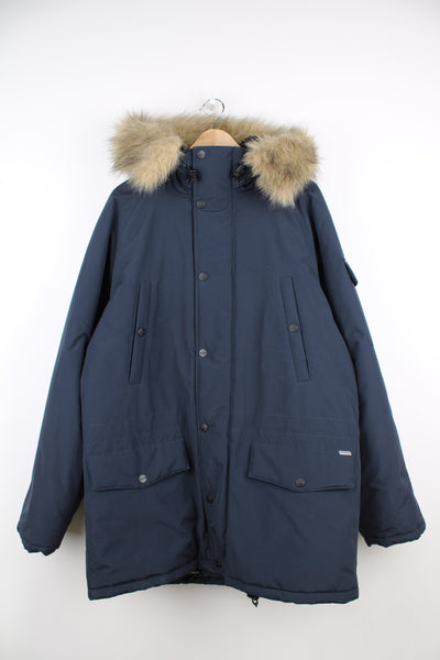 Carhartt Parka Jacket in a navy blue colourway, multiple pockets, insulated with a quilted lining, faux fur hood which is fleece lined, and has embroidered logo on the front and sleeve.