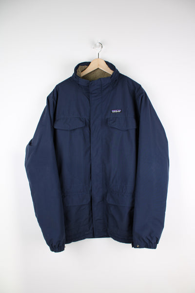Patagonia outdoor jacket in blue, zip up, multiple pockets, sherpa lining and has embroidered logo on the front.
