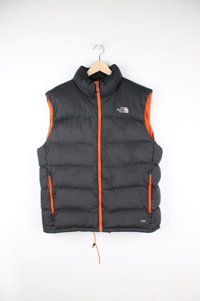 The North Face Face puffer gilet in a grey and orange, zip up with side pockets, insulated and has logo embroidered logo on the front and back.