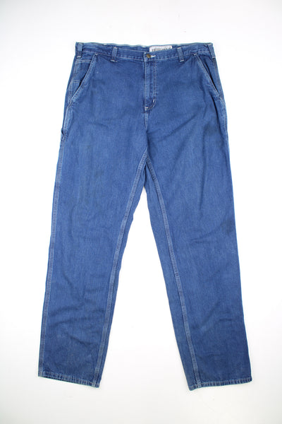 Carhartt Carpenter Jeans in a blue colourway with white cross stitching throughout, multiple pockets, and has the logo embroidered on the back pocket.