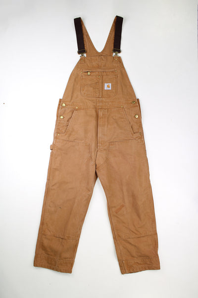 Vintage Carhartt tan denim dungarees with double knee reinforcement. Feature embroidered logo patch on the chest. good condition - Marks throughout (see photos) and the legs have been made slightly shorter (see measurements) Size in Label: 34 x 30 - Would estimate a Mens M