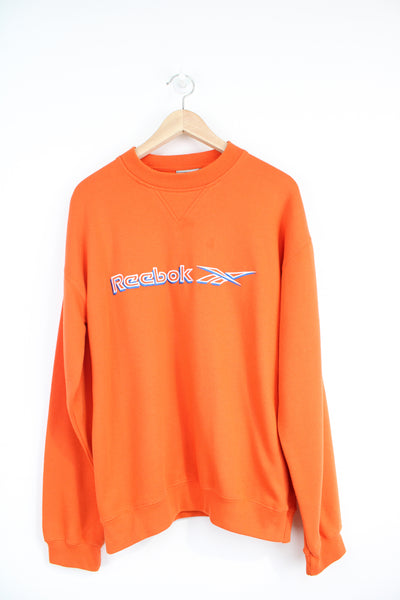 Bright orange Reebok crewneck sweatshirt with embroidered spell-out logo across the chest