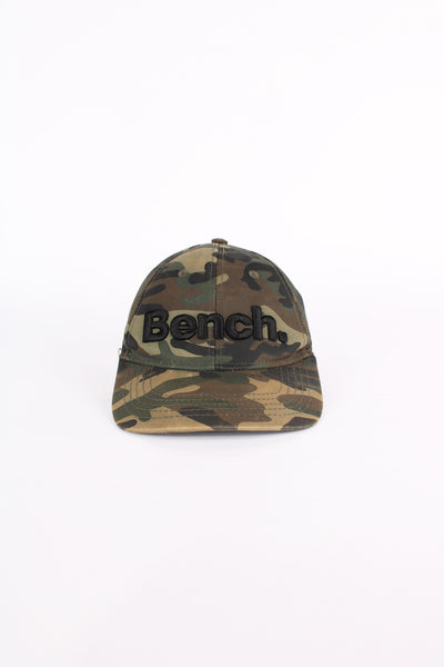 Y2K Bench camouflage baseball cap features embroidered spell-out logo across the front and adjustable velcro strap