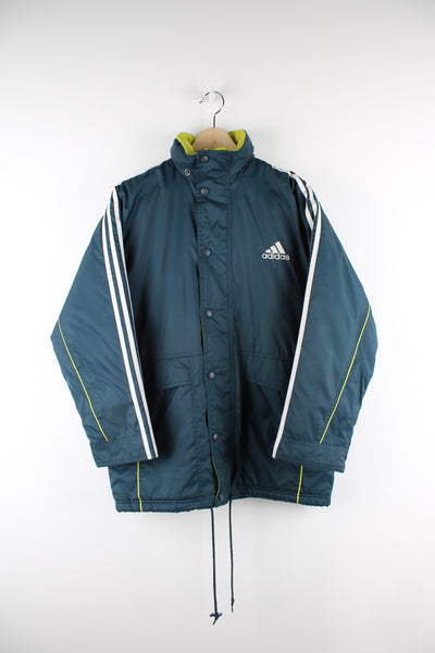 Vintage Adidas sports coat in dark green, has white stripes going down the sleeves, hidden hood, quilted lining, adjustable waist and logo embroidered on the front.