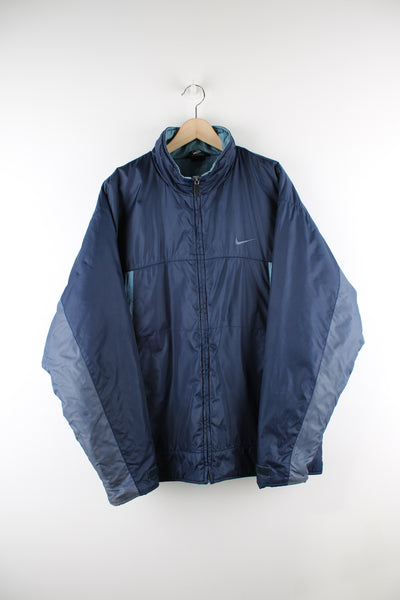 Vintage Nike Coach Jacket in a 2 tone blue colourway, zip up, insulated with a quilted lining, multiple pockets, and has logo embroidered on the front and spell-out across the back.