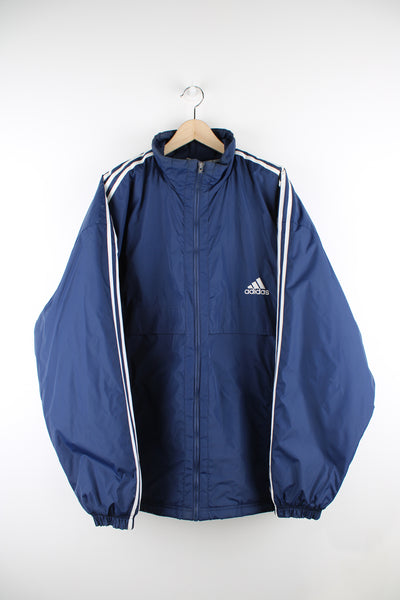 Vintage Adidas Sports Coat in blue with white stripes going down the sleeves, zip up, multiple pockets and has logo embroidered on the front. 