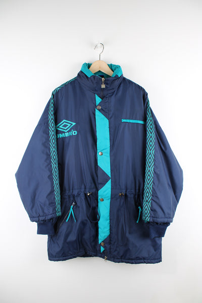 Vintage Umbro sports coats in a blue and green colourway, zip up, multiple pockets, insulated, has a hidden hood, adjustable and has logo embroidered on the front.