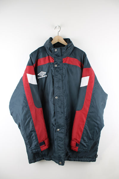 Vintage Umbro sports coat in a grey and red colourway, zip up, hidden hood, quilted lining and has the logo embroidered on the front. 