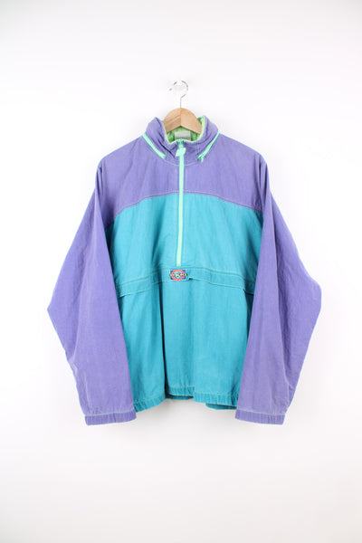 New Balance Pullover Windbreaker in a blue and purple colourway, half zip, hidden hood, side pockets, and has the logo embroidered on the front.
