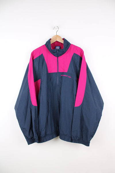 Vintage Umbro Pullover Windbreaker in a navy blue and pink colourway, half zip, side pockets, and has the logo embroidered on the front.
