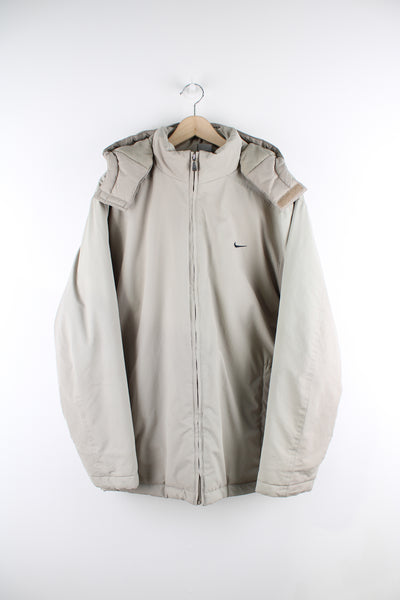 Vintage Nike outdoors jacket in a tan colourway, zip up, side pockets, detachable hood, insulated with a quilted lining, and has swoosh logo embroidered on the front and back.