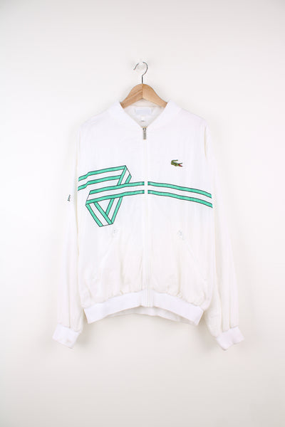 Vintage Lacoste Chemise Tracksuit Jacket in a white colourway with green pattern going round the jacket, zip up, side pockets, and has the logo embroidered on the front and right sleeve.