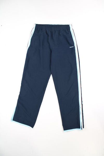 Vintage Navy blue Reebok tracksuit bottoms with elasticated waistband and 1/4 zips down the side of the ankles. Features white embroidered logo and stripe detail down the legs. good conditionSize in Label: Mens 30 - Measures like a Mens M