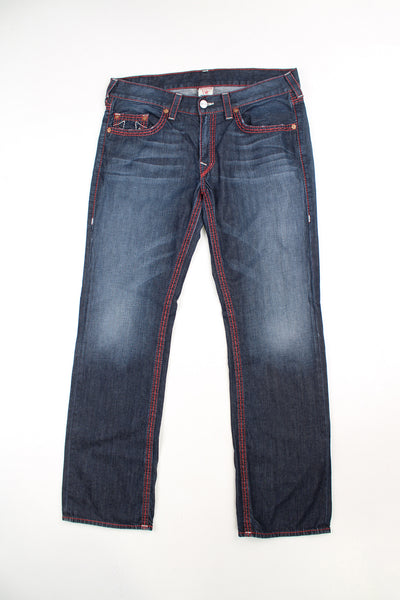 True Religion dark wash jeans, features red and white contrast stitching and signature logo on the back pockets 