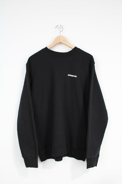 Patagonia black crew neck sweatshirt with spell-out logo on the chest and signature mountain graphic on the back