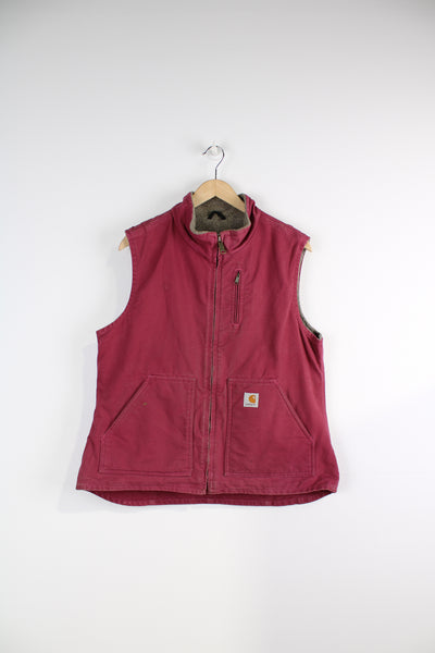 Carhartt Gilet in a pink colourway, zip up, multiple pockets, sherpa lining and has logo embroidered on the front. 