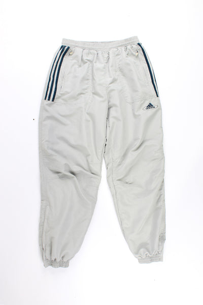 Adidas Tracksuit Bottoms in a tan colourway with the iconic 3 stripes going down the sides, has a elasticated waist, pockets, and logo embroidered on the front.