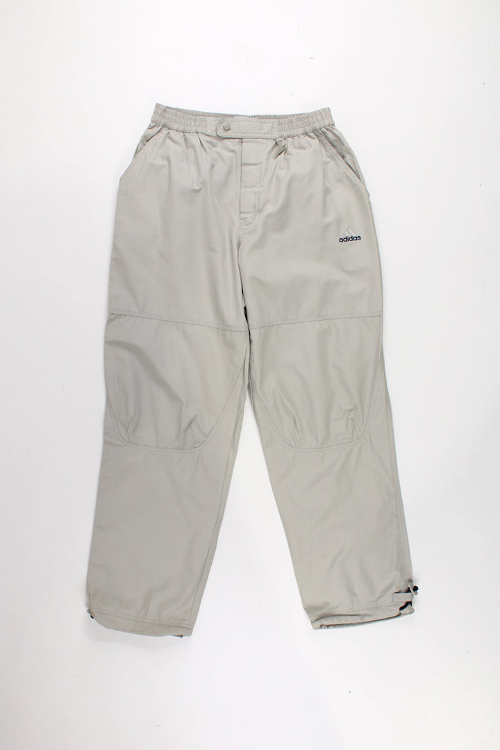 Adidas Tracksuit Bottoms in a tan colourway, has a elasticated waist, velcro fly, multiple pockets, and logo embroidered on the front.