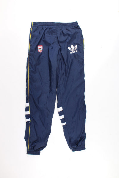 Vintage Arsenal 1991/93, Adidas Tracksuit Bottoms in a blue colourway with a yellow stripe going down the legs and 3 white stripes on the back, has a elasticated waist, pockets, and logos embroidered on the front.