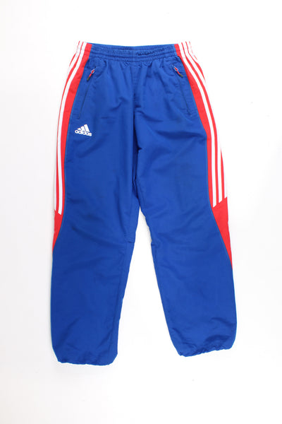 Adidas Tracksuit Bottoms in a blue and red colourway with the iconic 3 white stripes going down the legs, has a elasticated waist, pockets, and logo embroidered on the front.