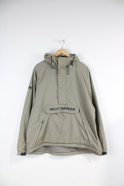Helly Hansen Pullover Jacket in a tanned colourway with blue embroidered spell-out logos on the front and sleeve, half zip, and has multiple pockets.