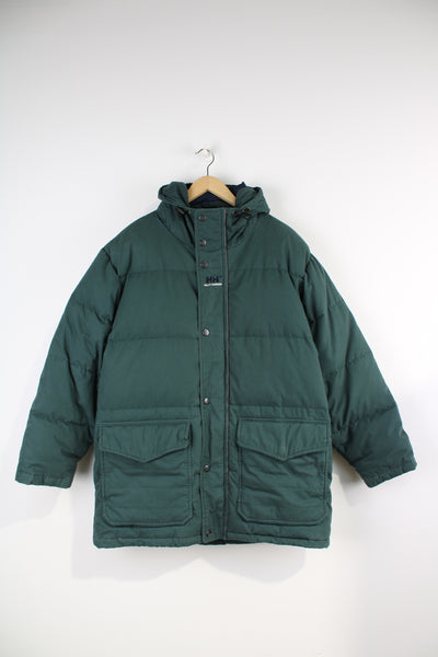 Helly Hansen Down Puffer Jacket in a dark green colourway, zip up, multiple pockets, insulated, hooded and has the logo embroidered on the chest. 