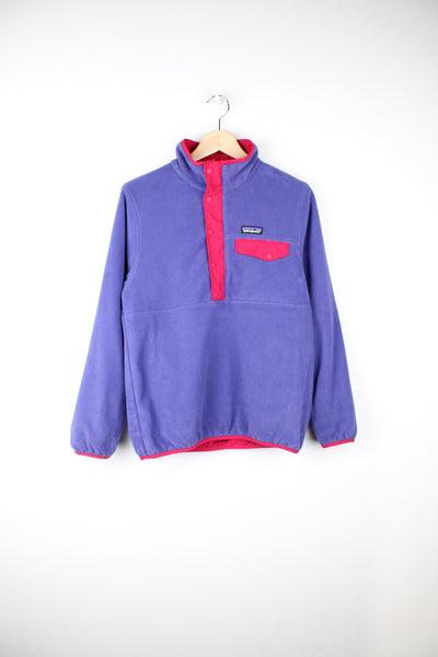 Patagonia Reversible Fleece in either a purple or pink colourway with a fleece or shell option, half zip, pockets and has the logo embroidered on the front.