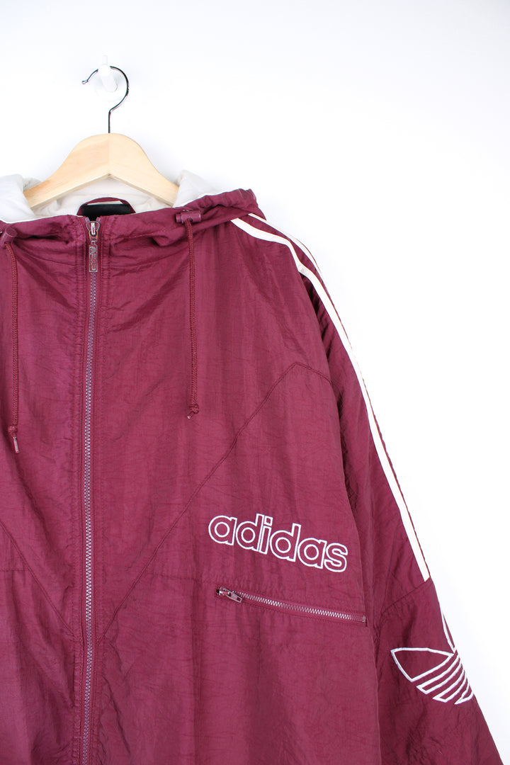 Vintage Adidas maroon red shell jacket with embroidered logo on the chest, embroidered three stripes down the arms and zip up pockets