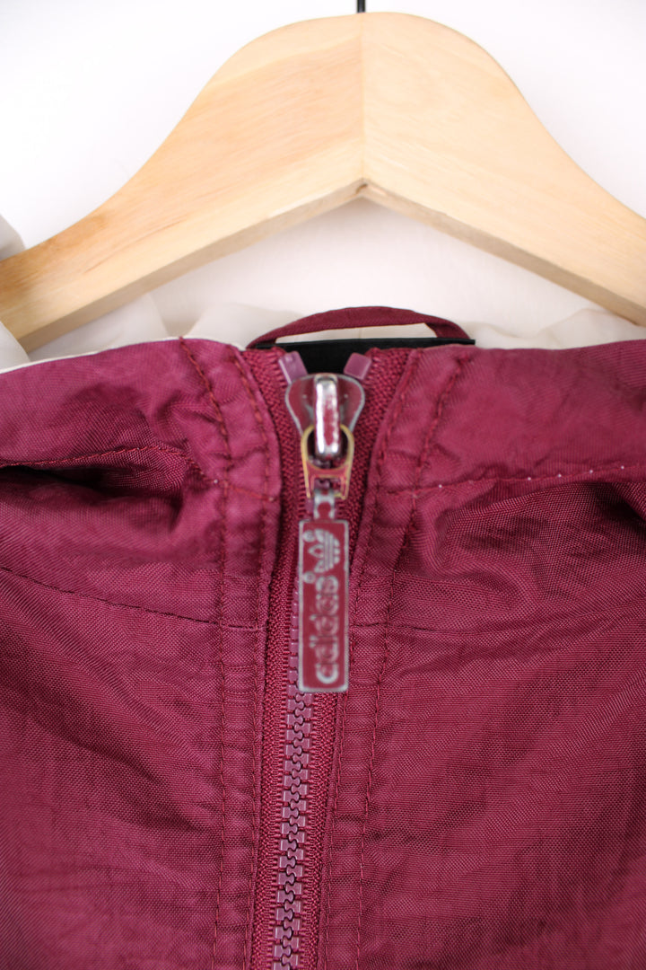 Vintage Adidas maroon red shell jacket with embroidered logo on the chest, embroidered three stripes down the arms and zip up pockets