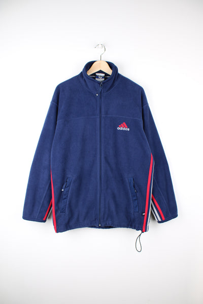 Adidas Fleece in a blue, red and white colourway, zip up, side pockets and has the logo embroidered on the front.