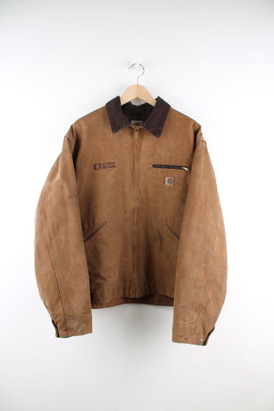 Carhartt Detroit Jacket in a brown colourway, zip up, multiple pockets, and has 'United Rentals' spell out logo embroidered on the front alongside the Carhartt logo.
