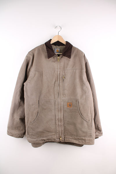 Carhartt Workwear Jacket in a sandy grey colourway with a brown collar, zip up, multiple pockets, sherpa quilted lining, and has the logo embroidered on the front.