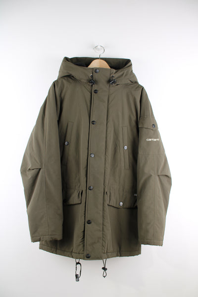 Carhartt Parka Jacket in a green colourway, multiple pockets, hooded with a faux fur lining, zip up, insulated quilted lining, and has the logo embroidered on the front and on the left sleeve.
