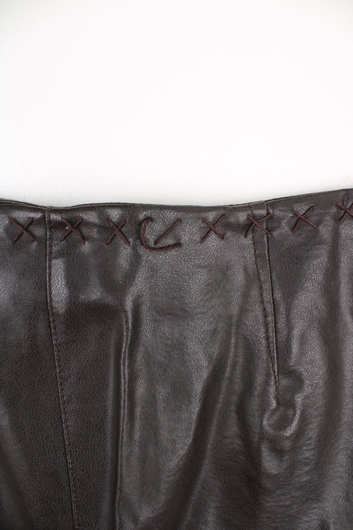 Vintage Leather Trousers in a brown colourway, mid rise, and has cross stitching design going around the waist and down the side of the legs.