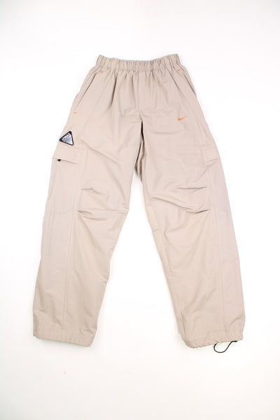 Nike Airmax Cargo Trousers in a tanned colourway, adjustable waist, multiple pockets, and has the logo embroidered on the front and side of the right leg.