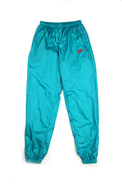 Vintage 90's Nike blue tracksuit bottoms with embroidered red logo on the top of the right leg, has a elasticated waist and cuffed at the bottom. 